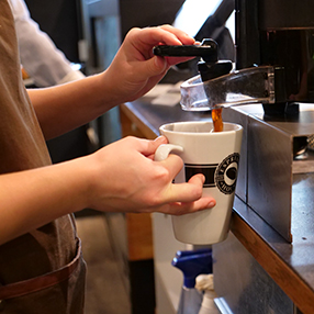 Barista fra Espresso House i Glostrup hælder kaffe i et krus.
